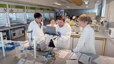 A group of students near the open laptop in the laboratory