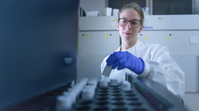 Person in a lab coat and blue gloves loading 300SL