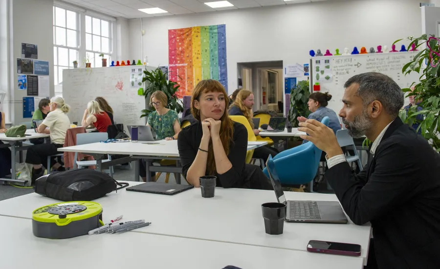 A group of people are shown seated at different tables in conversation.