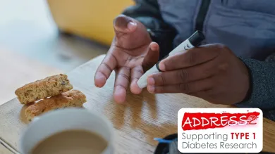 Person using a glucose meter on their fingertip beside a cup of coffee and biscotti on a table.