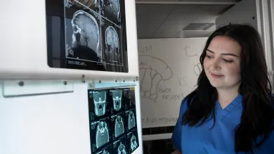 Healthcare student reviewing brain scan images on a medical display in a clinical learning environment.