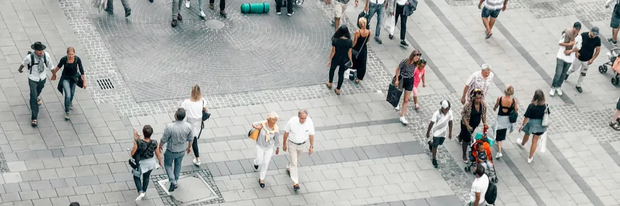 An aerial view of crowds of people walking in an urban environment.