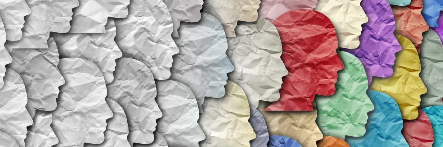 Crumpled paper cutouts of human profiles in gray transitioning to colourful shades.