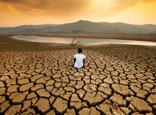 A man sit on dry land in an empty lake