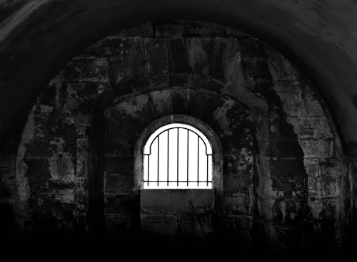 Dark prison cell with barred window
