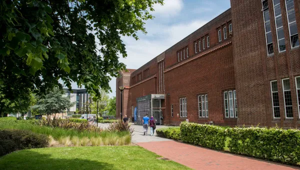 Exterior shot of academic building, trees and grass on a sunny day.