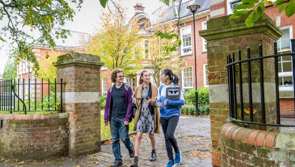 Students walking through gates outside the impressive buildings of Avenue Campus.