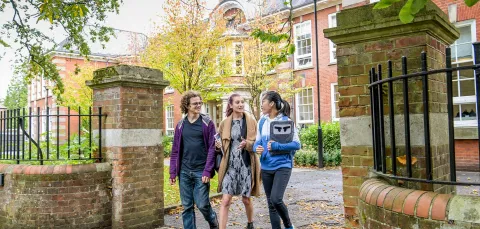 Students walking through gates outside the impressive buildings of Avenue Campus.