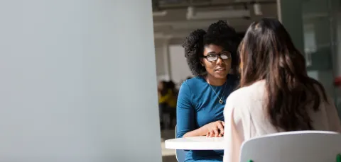 Adviser and student talking at a small table.