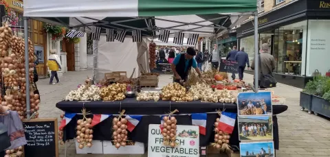 A market stall adorned with French flags, selling fresh fruit and vegetables.