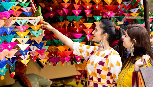 2 ladies shopping at a colourful stall during the Mela.