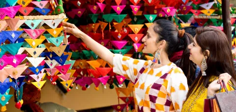 2 ladies shopping at a colourful stall during the Mela.