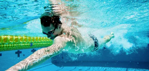 Man swimming under water in a swimming pool.