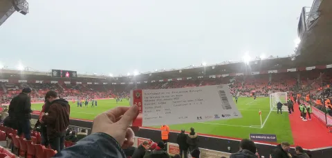 Student holding match ticket in the stands of St Mary's Stadium during a match.