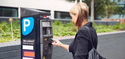 Visitor paying for car park at a parking machine. 