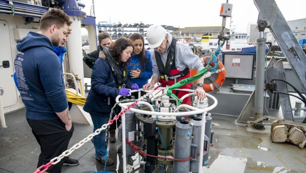 Students gathered around some tanks on the deck of the Callista ship