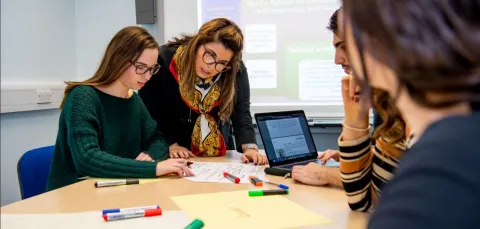 Education students taking part in small group learning using laptops and marker pens