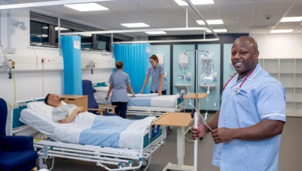 Nursing students working on a simulated ward with beds and drip