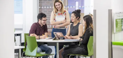 Four business students sitting around a table discussing their work
