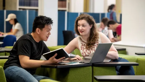 Two students collaborate on project work in a quiet learning space