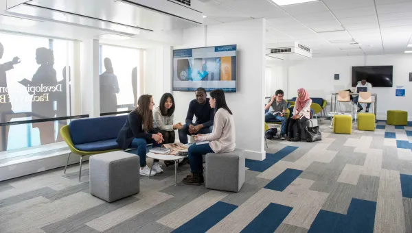 A small group of students sit and chat in a corner of the Business School study space.
