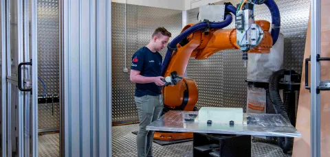 A student uses the robot arm in the engineering design and manufacturing centre