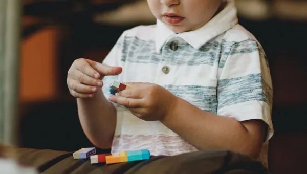 A child is absorbed in playing with brightly coloured building bricks