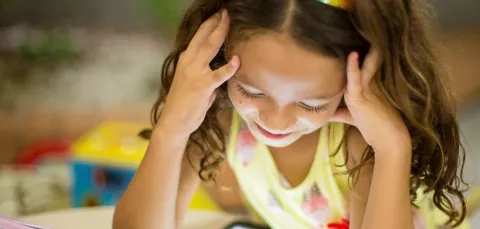 A young girl studies a tablet screen at a table
