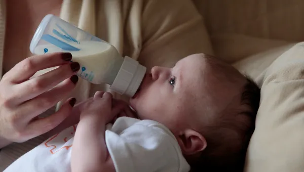 A mother feeds her baby from a bottle