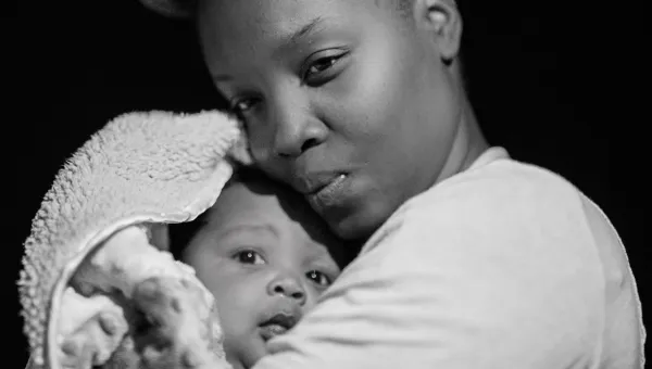 Black and white image of a mother holding her young baby close.