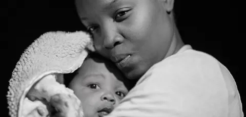 Black and white image of a mother holding her young baby close.