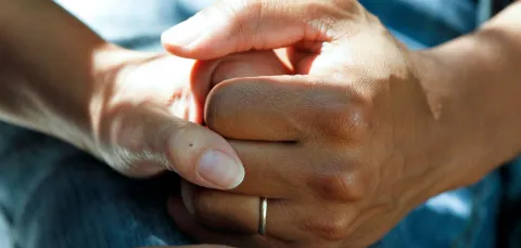 Comforting hands on a hospital bed