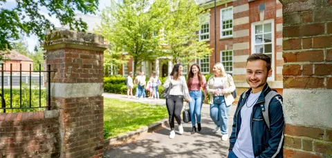 A student smiling at the gates of avenue campus