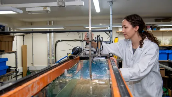 A student standing over a tank in the coastal lab facility