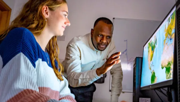 A member of the Southampton Geospatial team delivers training to a young person sitting in front of a screen with a visualisation of mapped data