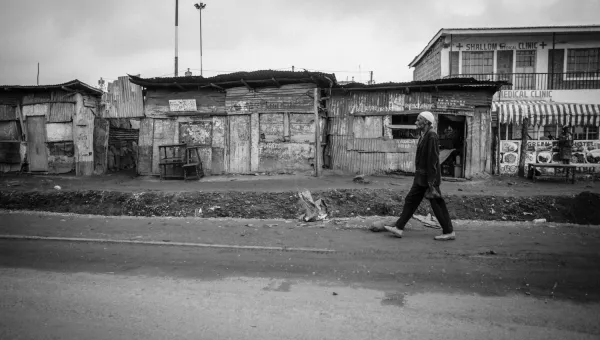 A black and white image of an elderly gentleman walking past a row of businesses in Nairobi, Kenya.