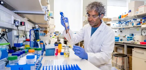 Professor Nullin Divecha working at a lab bench, surrounded by various containers and equipment.