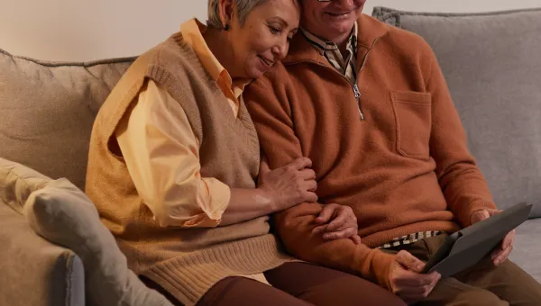 Pexels image of an older couple on a couch viewing a tablet screen