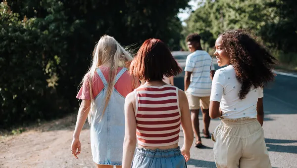 Teenagers walking down a sunny country lane away from the camera