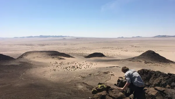 Man on top of rocks overlooking a desert