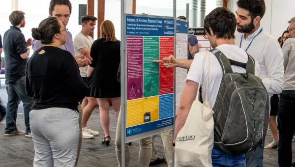 Researchers discussing an academic poster at an event