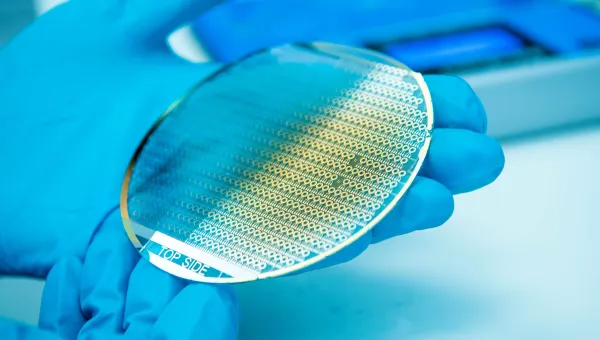 Pair of gloved hands holding a silicon disc chip