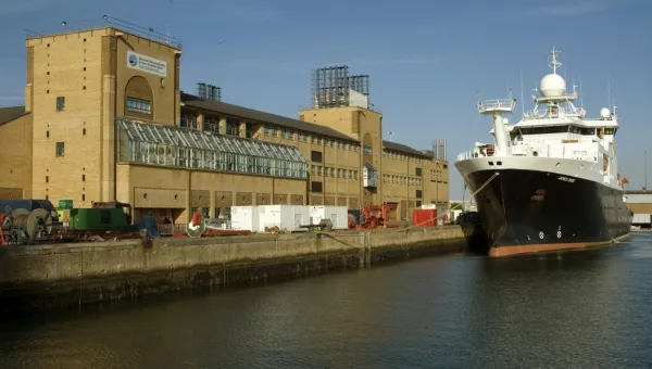 The long quayside frontage of the National Oceanography Centre, as seen from the water. A large research vessel sits on the water.