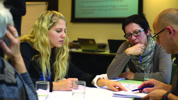 4 people around a table looking at a document
