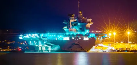 Night time image of a Queen Elizabeth Class Aircraft Carrier docked in Portsmouth Harbour