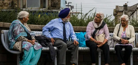 4 people from the Bangladeshi and Pakistani communities sitting on a bench talking