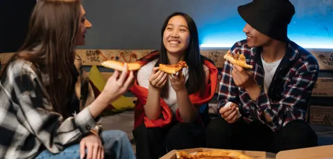 Three teenagers eating takeaway pizza
