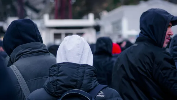 View looking at the backs of people with coats and hoodies on