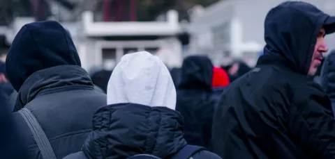 View looking at the backs of people with coats and hoodies on