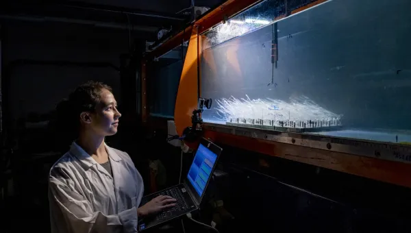A researcher with a laptop measuring underwater flow in a water tank